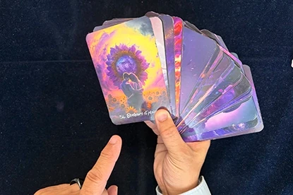 Mains tenant des cartes colorées pendant une consultation de voyance en cabinet à Genève